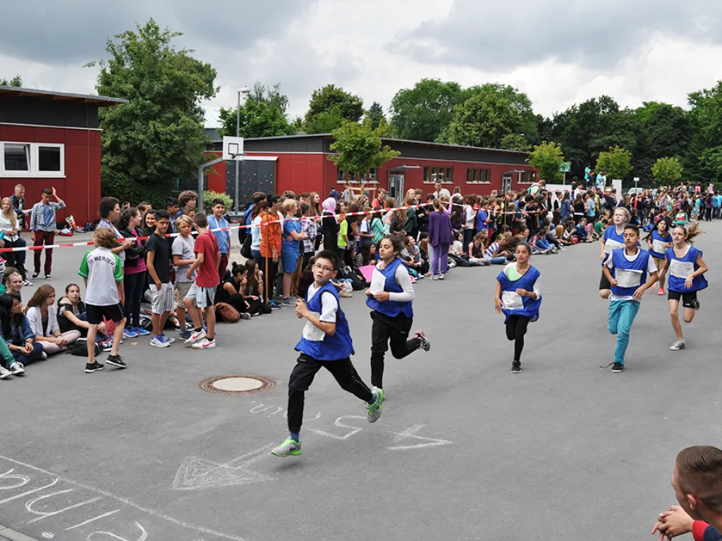 Läufergruppe startet vor dem Publikum auf dem Schulhof.